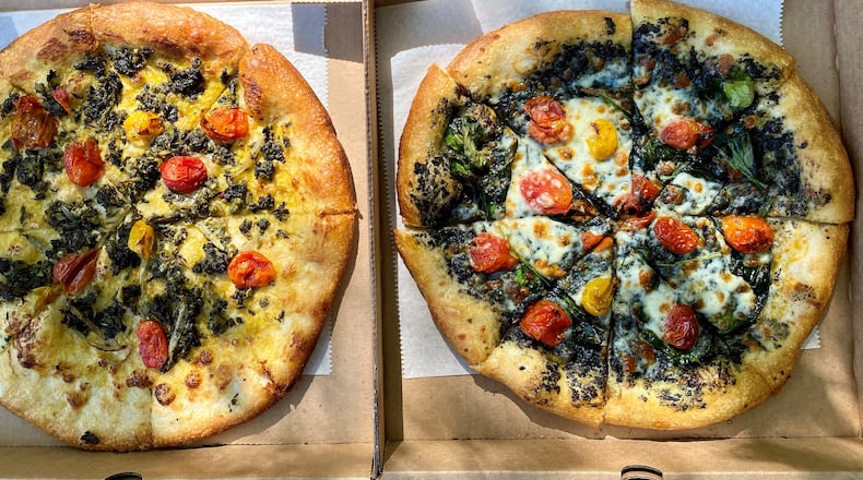 Dolos Pizza makes the Caribbean-inspired Vital pizza (left) with callaloo, roasted tomatoes and ackee sauce; and the Black pizza, with charcoal pesto, baby spinach, roasted tomatoes and mozzarella. Wendell Brock for The AJC