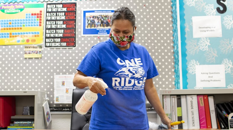 Leo Pineda, a custodian at Northbrook Middle School in Suwanee, Georgia, disinfects a teacher’s desk on Wednesday, July 8, 2020. Georgia superintendents are pushing for teachers to be designated essential workers to keep them in the classroom if exposed to COVID-19 but not showing symptoms. REBECCA WRIGHT FOR THE ATLANTA JOURNAL-CONSTITUTION