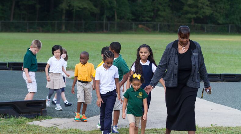 Elementary school principal Dr. Cassandra Hopkins leads the students in from the playground after a portrait session about school uniforms Wednesday, August 2, 2015, at McGarrah Elementary School in Morrow, GA. STEVE SCHAEFER / SPECIAL TO THE AJC
