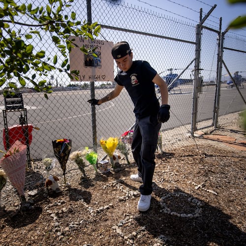A person adjusts flowers at a memorial for Eliana Moreno and George Marciniw who died in a helicopter crash at the site where their helicopter used to park at Whiteman Airport in Los Angeles, Wednesday, Sept. 16, 2026. (AP Photo/Ethan Swope)