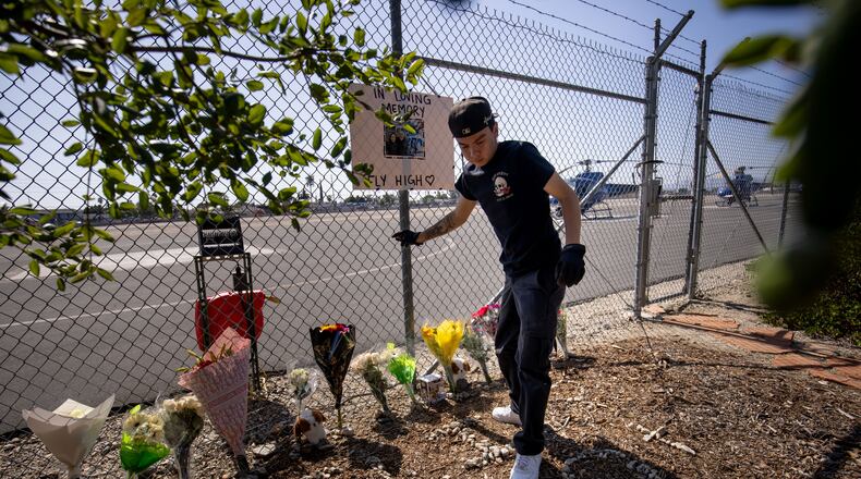 A person adjusts flowers at a memorial for Eliana Moreno and George Marciniw who died in a helicopter crash at the site where their helicopter used to park at Whiteman Airport in Los Angeles, Wednesday, Sept. 16, 2026. (AP Photo/Ethan Swope)