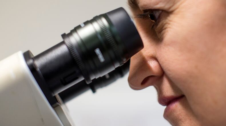 A Scientist looks at cells through a fluorescent microscope.
