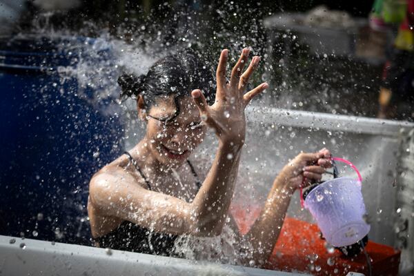 A woman reacts as water is splashed on her during the Songkran water festival to celebrate the Thai New Year in Prachinburi Province, Sunday, April 13, 2025. (AP Photo/Wason Wanichakorn)