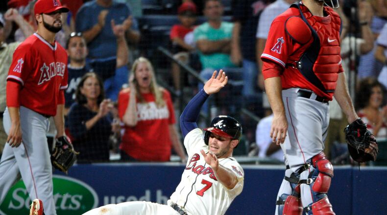 Atlanta Braves' Tommy La Stella (7) scores behind Los Angeles Angels catcher Chris Iannetta, right, while Angels pitcher Cam Bedrosian looks on during the tenth inning of a baseball game on Saturday, June 14, 2014, in Atlanta. (AP Photo/David Tulis)