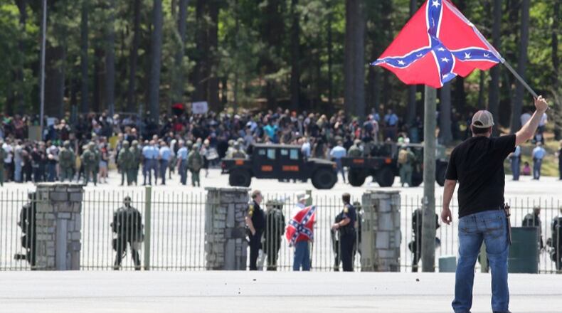 Joseph Andrews, one of a small group with the Rock Stone Mountain rally, waves a confederate battle flag towards a mass of counter-protesters more than 100 yards away at Stone Mountain Park on Saturday afternoon April 23, 2016 where a white power protest and two counter protests were scheduled.