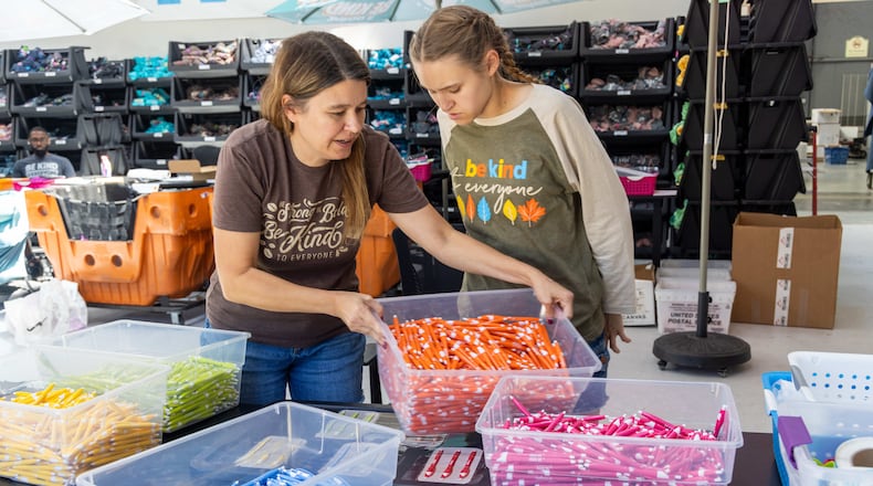 Jackie Moore (left) helps set up a work station for her daughter Jordyn at the Summer Shirt Project warehouse in Cumming. Her family started a business, the Summer Shirt Project, to create a job that Jordyn, who has autism, could thrive in. PHIL SKINNER FOR THE ATLANTA JOURNAL-CONSTITUTION