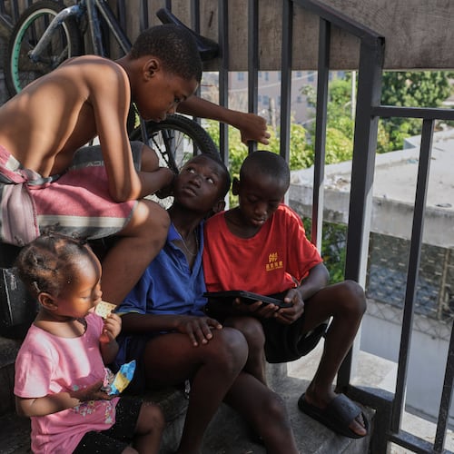 Children watch a movie on a mobile device at a shelter for families displaced by gang violence in Port-au-Prince, Haiti, Wednesday, Aug. 19, 2026. (AP Photo/Odelyn Joseph)