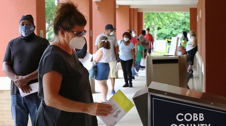 051820 Marietta: Nina Wilson drops off her absentee ballot while dozens of other voters line up to cast their votes in person on the first day of early voting at the Cobb County Board of Elections & Registration on Monday, May 18, 2020, in Marietta.   Curtis Compton ccompton@ajc.com