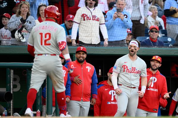 Philadelphia Phillies' Bryce Harper, second from right, reacts as Kyle Schwarber (12) comes back to the dugout after his home run in the seventh inning of an opening-day baseball game against the Washington Nationals, Thursday, March 27, 2025, in Washington. (AP Photo/Nick Wass)