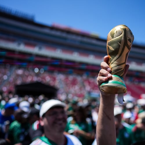 A fan holds up a replica of the World Cup trophy at a fan festival at the Los Angeles Memorial Coliseum in Los Angeles, Thursday, June 11, 2026, during a live broadcast of the World Cup soccer match between Mexico and South Africa. (AP Photo/Jae C. Hong)