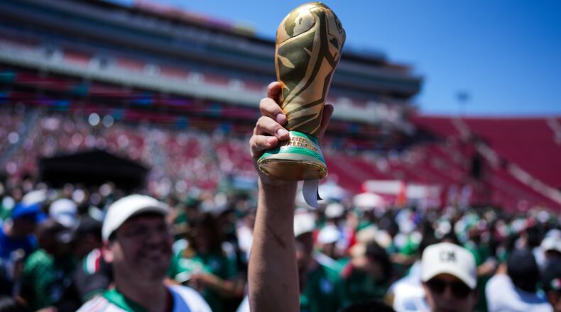 A fan holds up a replica of the World Cup trophy at a fan festival at the Los Angeles Memorial Coliseum in Los Angeles, Thursday, June 11, 2026, during a live broadcast of the World Cup soccer match between Mexico and South Africa. (AP Photo/Jae C. Hong)