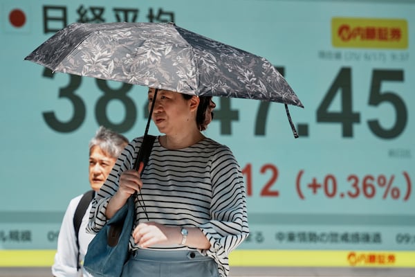 People walk in front of an electronic stock board showing Japan's Nikkei index at a securities firm Tuesday, June 17, 2025, in Tokyo. (AP Photo/Eugene Hoshiko)
