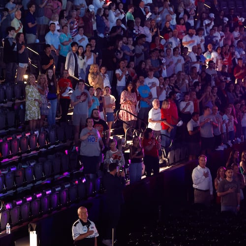 Attendees stand for the national anthem before a Turning Point USA event near the University of Georgia on Tuesday, April 14, 2026. (Arvin Temkar/AJC)