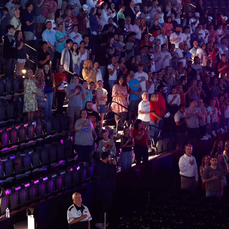 Attendees stand for the national anthem before a Turning Point USA event near the University of Georgia on Tuesday, April 14, 2026. (Arvin Temkar/AJC)
