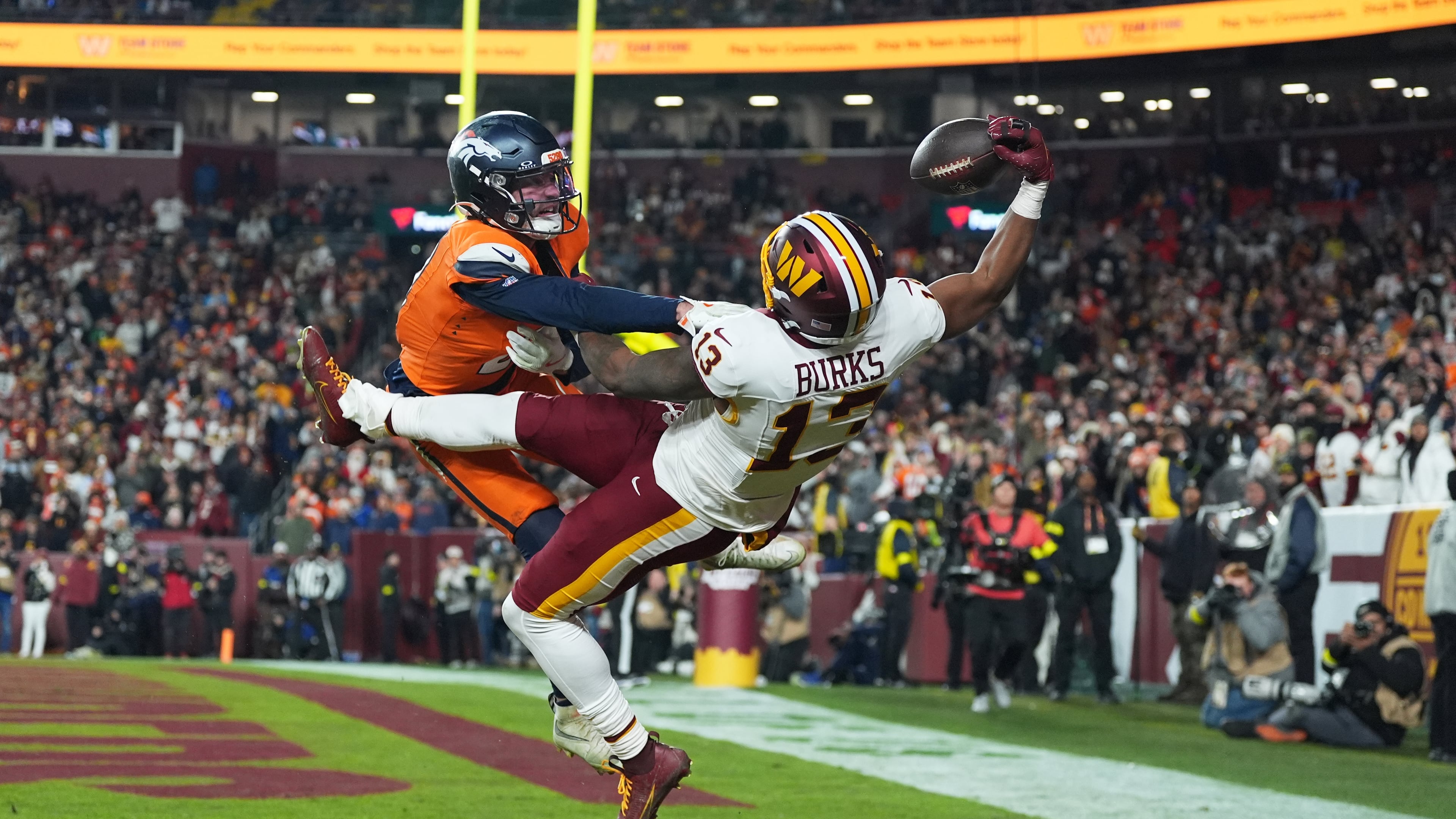 Washington Commanders wide receiver Treylon Burks (13) catches a touchdown pass as Denver Broncos cornerback Riley Moss, left, defends during the second half of an NFL football game Sunday, Nov. 30, 2025, in Landover, Md. (AP Photo/Stephanie Scarbrough)