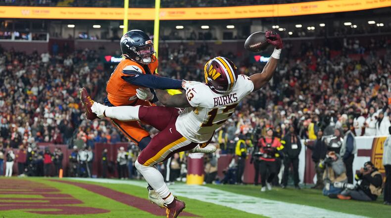 Washington Commanders wide receiver Treylon Burks (13) catches a touchdown pass as Denver Broncos cornerback Riley Moss, left, defends during the second half of an NFL football game Sunday, Nov. 30, 2025, in Landover, Md. (AP Photo/Stephanie Scarbrough)