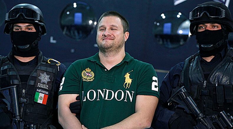 FILE - In this Aug. 31, 2010, file photo, Federal Police escort Texas-born fugitive Edgar Valdez Villarreal, center, stands during his presentation to the media in Mexico City. Villareal, known as "La Barbie" because of his light eyes and complexion, appeared before a federal judge Wednesday, Jan. 6, 2016, in Atlanta. He pleaded guilty to charges of conspiring to import and distribute cocaine and conspiring to launder money. (AP Photo/Alexandre Meneghini, File)