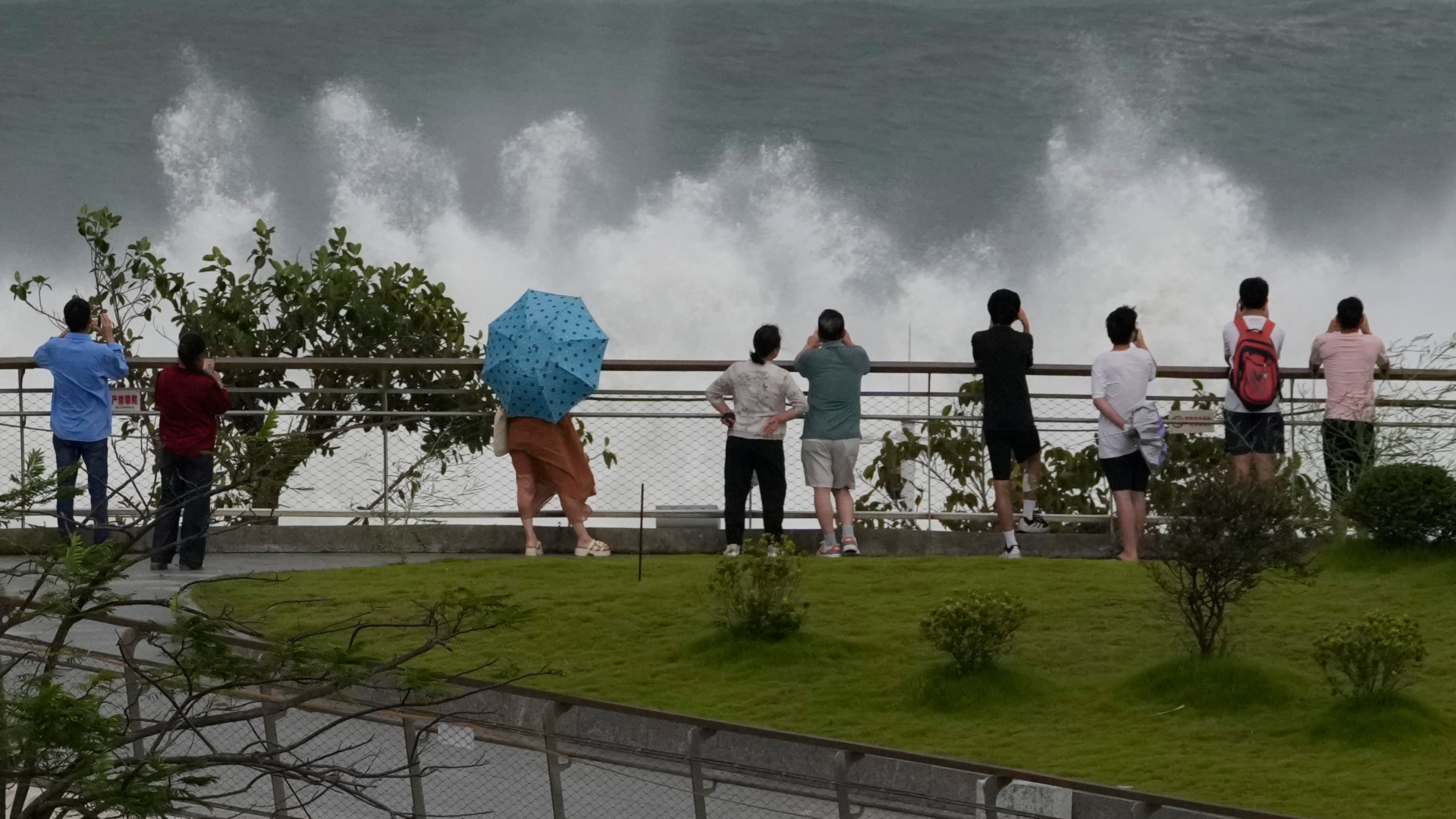 Residents brace strong winds as they watch waves crashing on a seaside ahead of Super Typhoon Ragasa in Shenzhen in southern China's Guangdong province on Tuesday, Sept. 23, 2025. (AP Photo/Ng Han Guan)