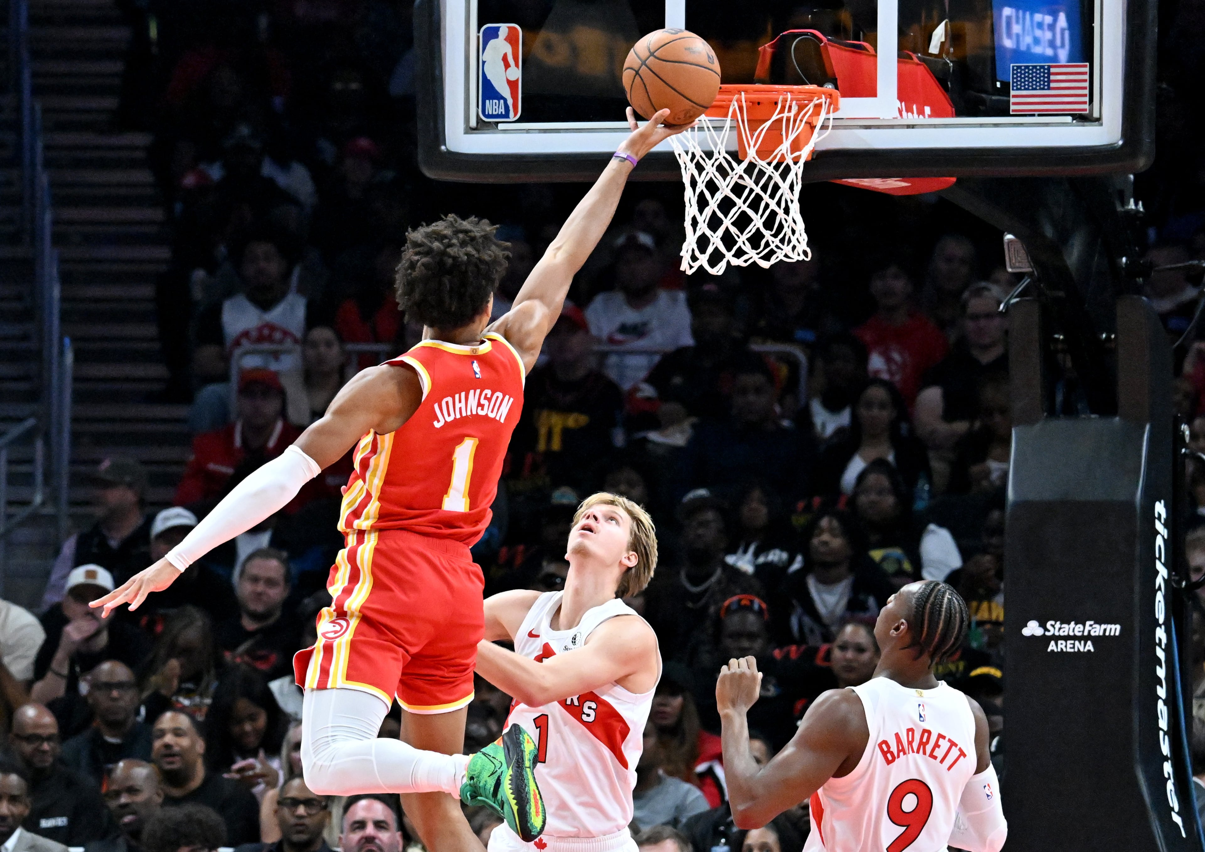 Atlanta Hawks forward Jalen Johnson (1) goes in for a lay-up over Toronto Raptors guard/forward Gradey Dick (1) during the first half in the home opener at State Farm Arena, Thursday, October 22, 2025, in Atlanta. (Hyosub Shin / AJC)
