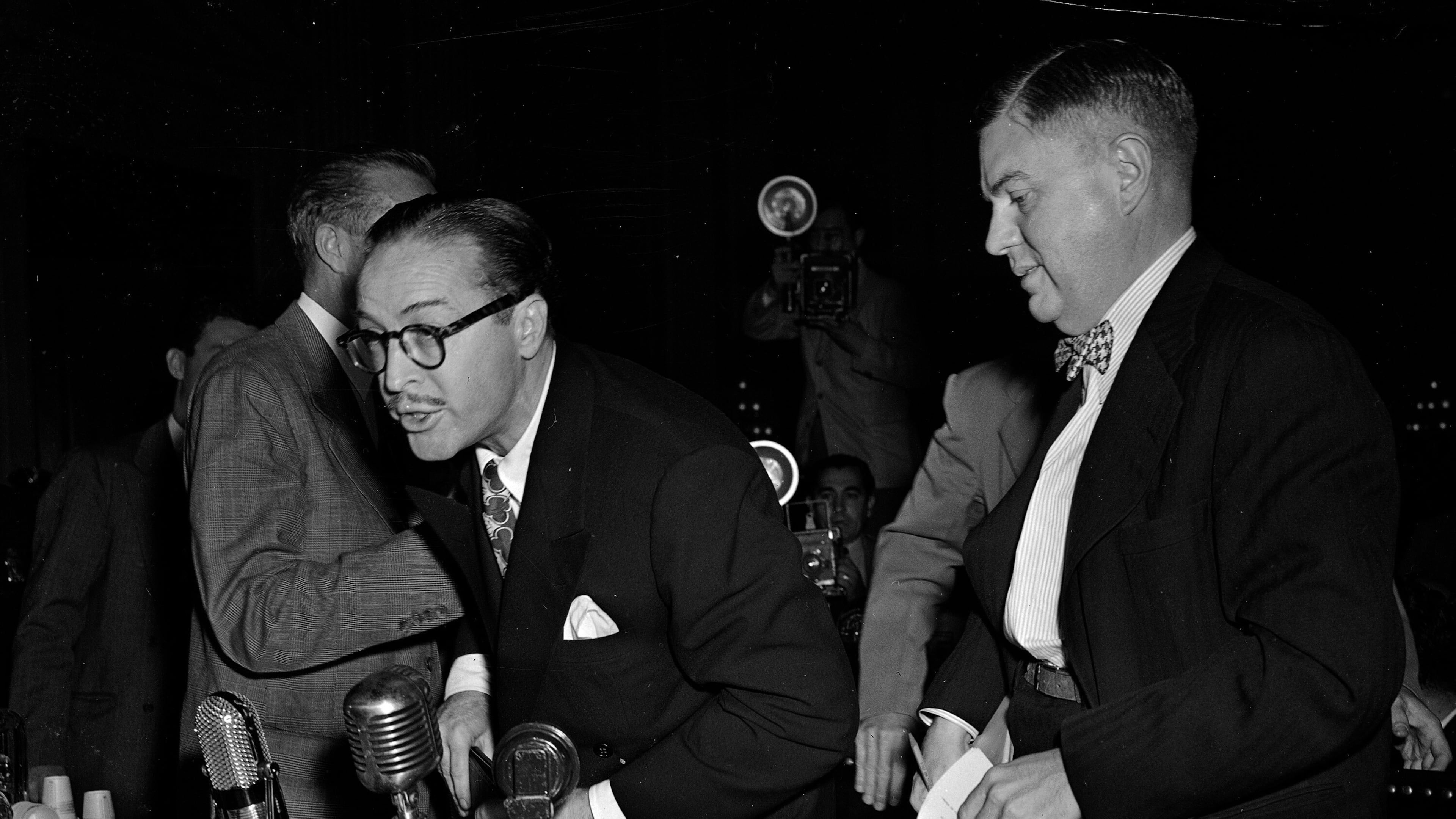 FILE - Dalton Trumbo, left, Hollywood screenwriter, shouts from the witness stand as he tries to make a statement before the House Un-American Activities Committee, Oct. 28, 1947, in Washington. At right is his attorney Robert Kenny. Trumbo was excused from further testimony when he refused to state whether he is or has been a communist. (AP Photo/Byron Rollins, File)