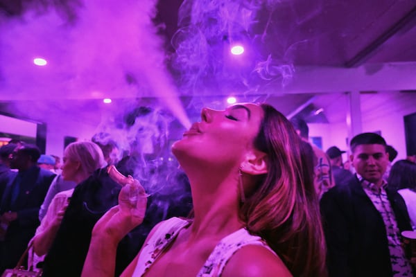 FILE - A guest takes a puff from a marijuana cigarette at the Sensi Magazine party celebrating the 420 holiday in the Bel Air section of Los Angeles, April 20, 2019. (AP Photo/Richard Vogel, File)