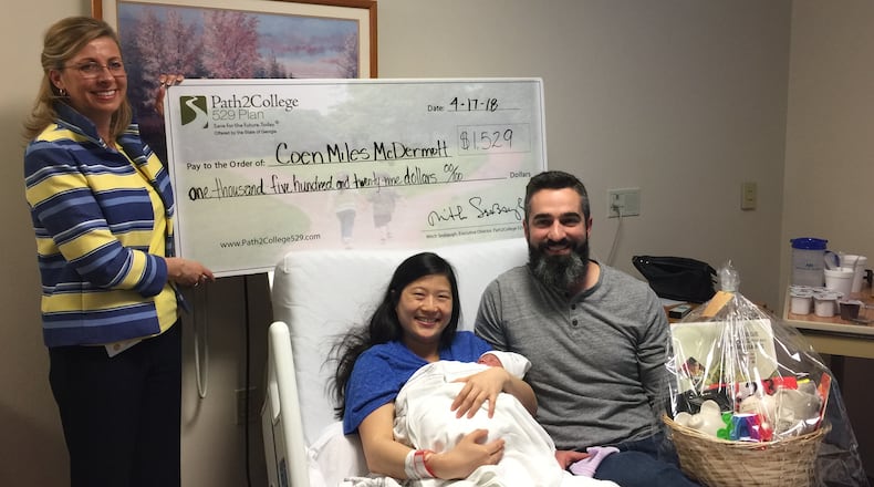 Jennifer Herring presents Anna and Mike McDermott with a check for $1,529 for Coen, the first “Tax Day Baby” born at Northside Hospital in 2018.