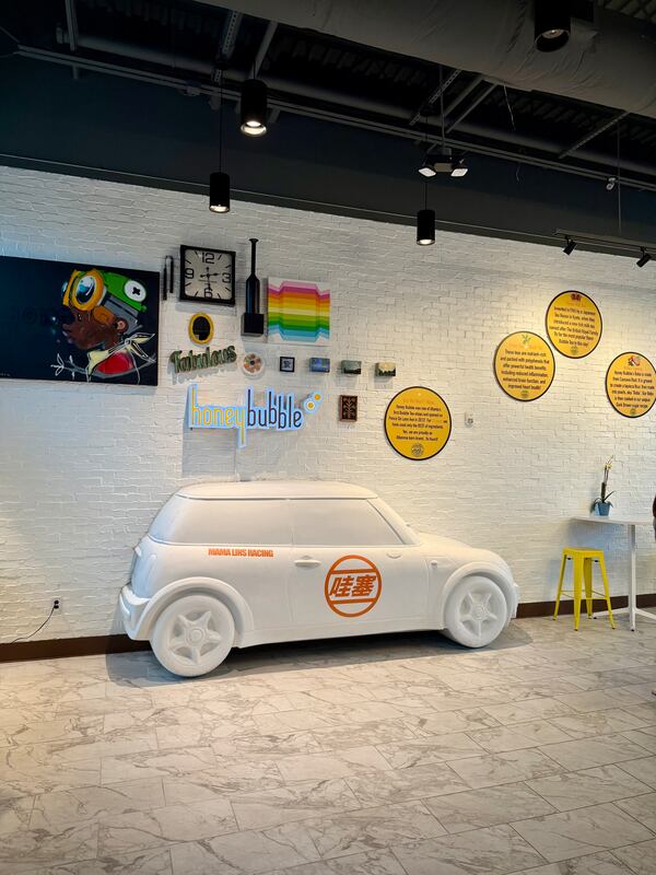 A restaurant interior decorated with colorful pop art-style wall pieces and a life-size sculpture of a Mini Cooper protruding from the wall.