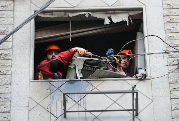Rescue workers remove an air-condition compressor from a damaged apartment at the site of an Israeli airstrike on Dahiyeh in the southern suburb of Beirut, Lebanon, Sunday, April 27, 2025. (AP Photo/Hussein Malla)