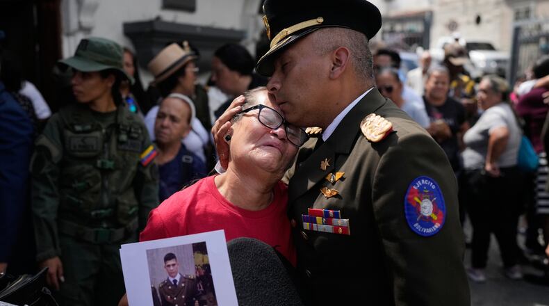 A military officer comforts Ramona Palma, the mother of Venezuelan soldier Cesar Garcia, who was killed in a U.S. raid that captured Venezuelan President Nicolas Maduro, after Garcia's wake in Caracas, Venezuela, Wednesday, Jan. 7, 2026. (AP Photo/Matias Delacroix)