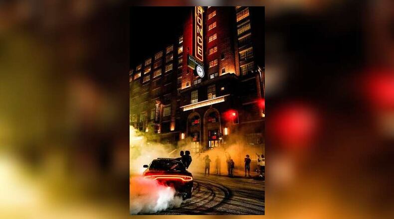 As bystanders look on, a car does doughnuts in front of Ponce City Market in Atlanta.