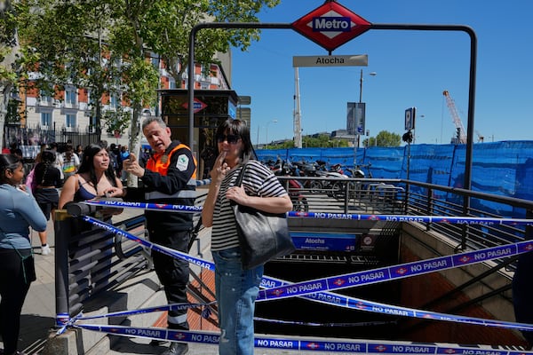 A security guard speaks with a woman outside a temporarily closed metro station during a nationwide power outage in Madrid, Monday, April 28, 2025. (AP Photo/Manu Fernandez)
