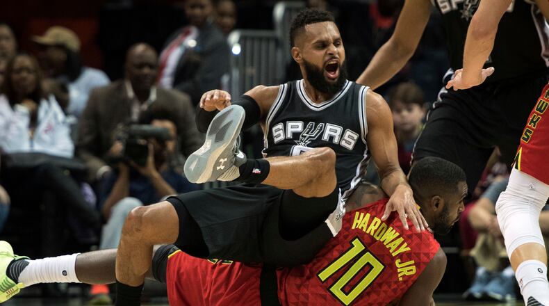 San Antonio Spurs guard Patty Mills, top, of Australia, falls on Atlanta Hawks guard Tim Hardaway Jr. while going for the ball during the first half of an NBA basketball game, Sunday, Jan. 1, 2017, in Atlanta. (AP Photo/John Amis)