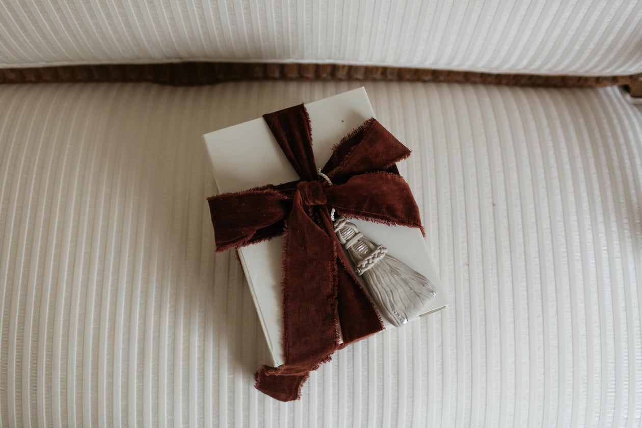 A gift wrapped with Page House Studio’s sculptural Tassel Ornament — a handcrafted piece that doubles as a keepsake and one of the Atlanta design studio’s most elevated holiday offerings. (Courtesy of Anna Howard)