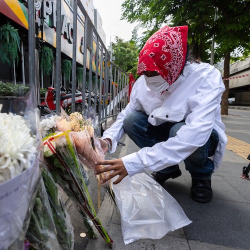 A man puts flowers outside the music bar where a fire killed a number of people in Bangkok, Thailand, Tuesday, July 14, 2026. (AP Photo/Wason Wanichakorn)
