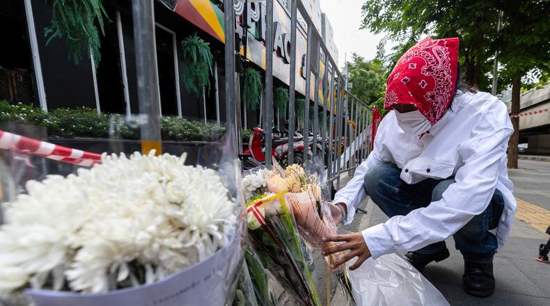 A man puts flowers outside the music bar where a fire killed a number of people in Bangkok, Thailand, Tuesday, July 14, 2026. (AP Photo/Wason Wanichakorn)