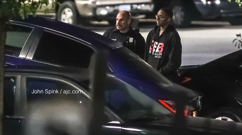 Morehouse College student Deaven Rector, 19, stands with an Atlanta police officer as authorities tow away his Toyota Corolla for processing. Rector’s car was stolen from him in southwest Atlanta Tuesday morning and later recovered.