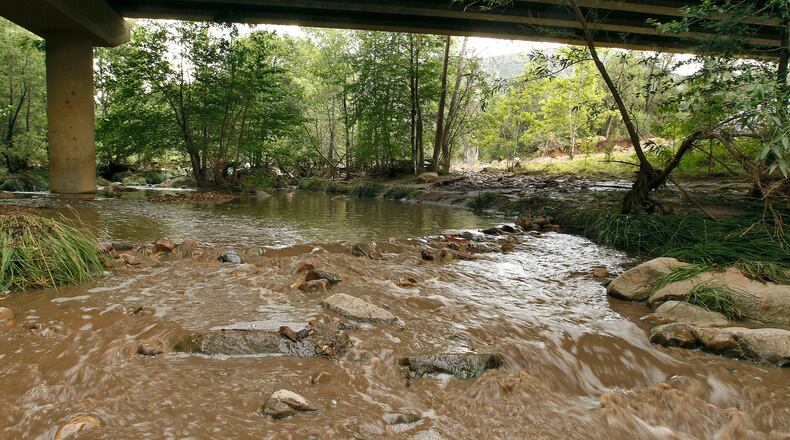 Muddy floodwaters of the East Verde River flow under a bridge where one victim of the flash flood was found during a search and rescue operation by the Gila County Sheriff's Office on Sunday, July 16, 2017, in Payson, Ariz. Search and rescue crews, including 40 people on foot and others in a helicopter, have recovered bodies of children and adults, some as far as two miles down the river after Saturday's flash flooding.