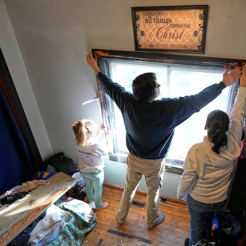 Gerard Berry, along with his wife, Stephanie, and daughter, Brooklynn, cover a bedroom window with plastic, Friday, Nov. 7, 2025, in Baileyville, Maine. (AP Photo/Robert F. Bukaty)