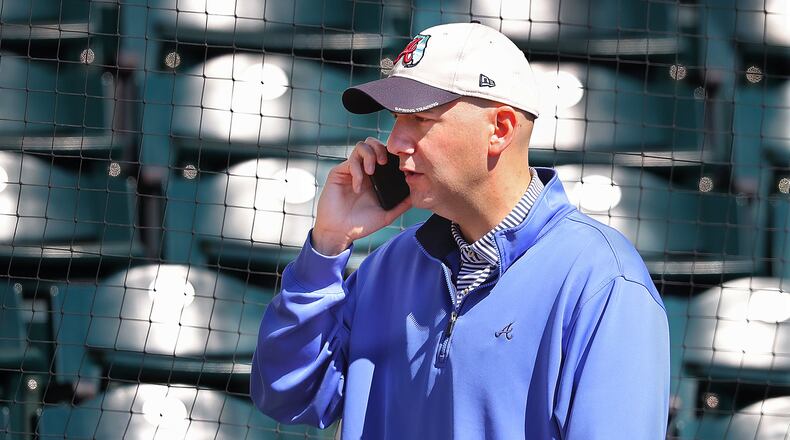 Braves general manager John Coppolella works the phone while watching the team’s spring-training workout. (Curtis Compton/ccompton@ajc.com)