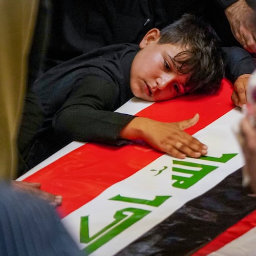 A child rests his head on the coffin of a Popular Mobilization Forces fighter draped in the Iraqi flag during a funeral for Popular Mobilization Forces fighters killed in airstrikes on PMF bases in Najaf, Iraq, Thursday, July 30, 2026. (AP Photo/Anmar Khalil)