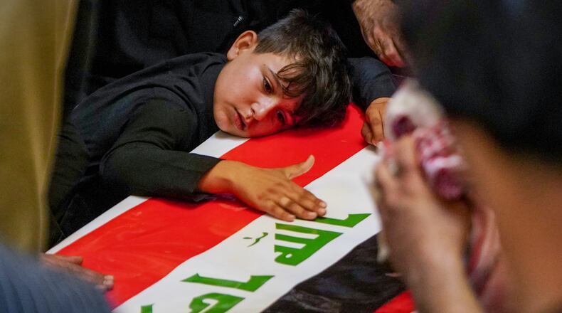 A child rests his head on the coffin of a Popular Mobilization Forces fighter draped in the Iraqi flag during a funeral for Popular Mobilization Forces fighters killed in airstrikes on PMF bases in Najaf, Iraq, Thursday, July 30, 2026. (AP Photo/Anmar Khalil)