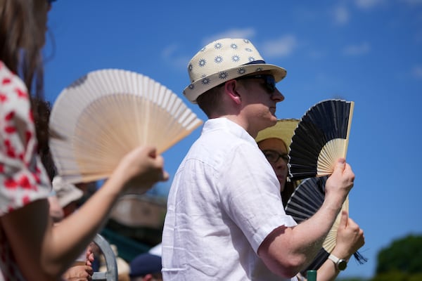 Visitors use a fan to stay cool at the Wimbledon Tennis Championships in London, Monday, June 30, 2025. (AP Photo/Kin Cheung)