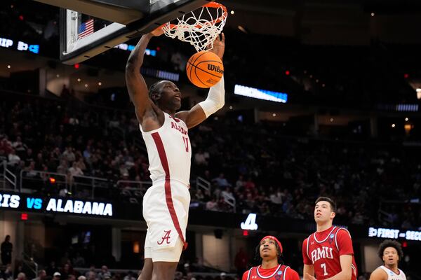 Alabama center Clifford Omoruyi, left, dunks in front of Robert Morris guard DJ Smith, center, and forward Alvaro Folgueiras, right, in the first half in the first round of the NCAA college basketball tournament, Friday, March 21, 2025, in Cleveland. (AP Photo/Sue Ogrocki)
