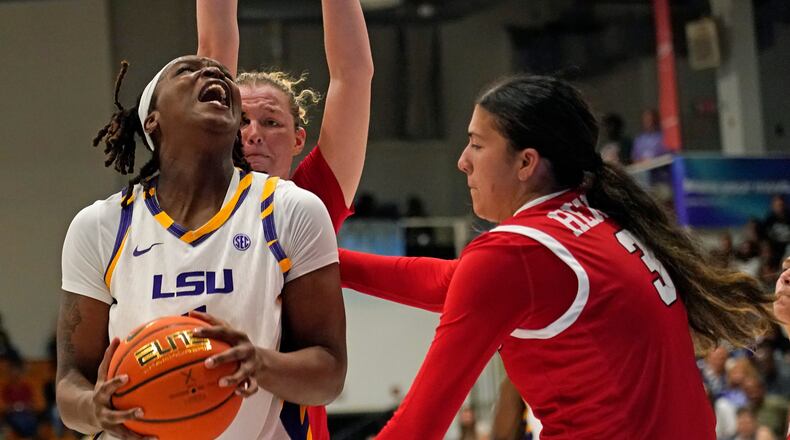 LSU forward Amiya Joyner, left front, drives the lane against Marist guard Justine Henry, right, and forward Karly Fischer , left back, during the second quarter of an NCAA college basketball game at the Paradise Jam tournament Friday, Nov. 28, 2025, in St. Thomas, U.S. Virgin Islands. (Bill Kiser/The Virgin Islands Daily News via AP)