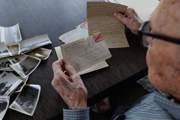 Alan Kinder looks through old photos and letters he wrote to loved ones. Kinder, along with other WWII veterans, will visit Normandy for the commemoration of the 80th anniversary of D-Day in June. ( Natrice Miller/ AJC)