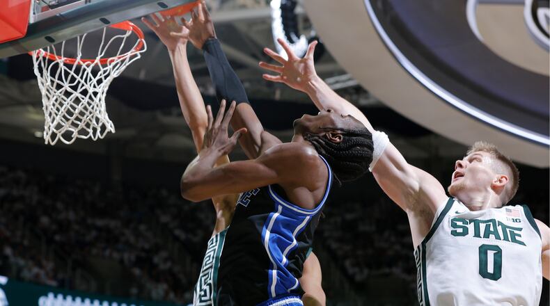 Duke guard Dame Sarr, center, and Michigan State forward Jaxon Kohler (0), right, and forward Jordan Scott, rear, vie for a rebound during the first half of an NCAA college basketball game, Saturday, Dec. 6, 2025, in East Lansing, Mich. (AP Photo/Al Goldis)