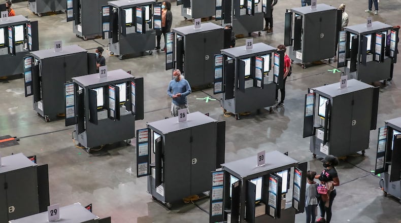 Voters finally got to the machines after a glitch forestalled voting on Monday, Oct. 12, 2020 at State Farm Arena in downtown Atlanta. Eager Georgia voters swarmed to polling places Monday morning, waiting in lines created by high turnout and technical problems at the start of three weeks of early voting before Election Day. A glitch with voter check-in computers held up voters at Georgia’s largest early voting site at State Farm Arena. Lines stopped after voters received an “invalid card” error when inserting green voter access cards into touchscreens. Poll workers had to reboot the arena’s 60 voter check-in tablets and re-import voter information, said Fulton Elections Director Richard Barron. “We apologize to all the voters,” Barron said. (John Spink / John.Spink@ajc.com)
