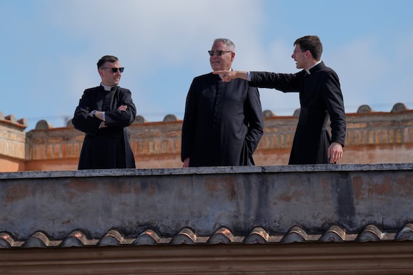 Priests stand on a rooftop balcony overlooking St Peter's Basilica during the conclave, at the Vatican, Wednesday, May 7, 2025. (AP Photo/Gregorio Borgia)