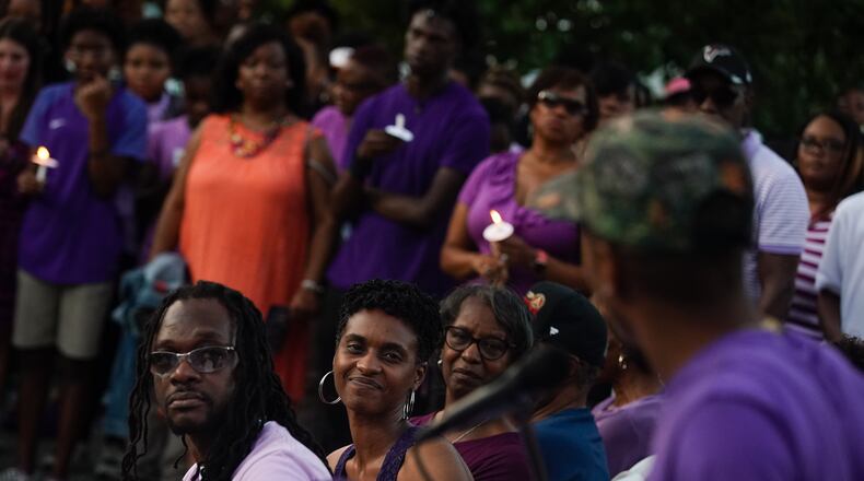 Imani Bell's parents look on as the teen's former coach speaks during Wednesday candlelight vigil.