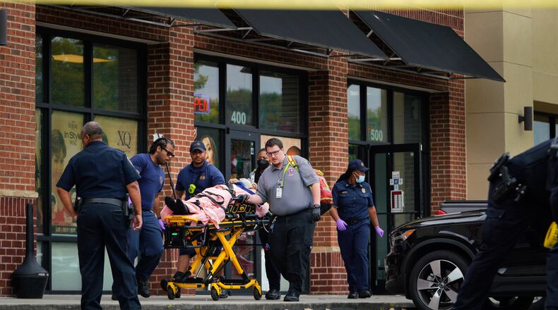 Medical personnel take a gunshot victim to a waiting ambulance outside the Luxury Nail Salon on Cleveland Avenue in East Point.